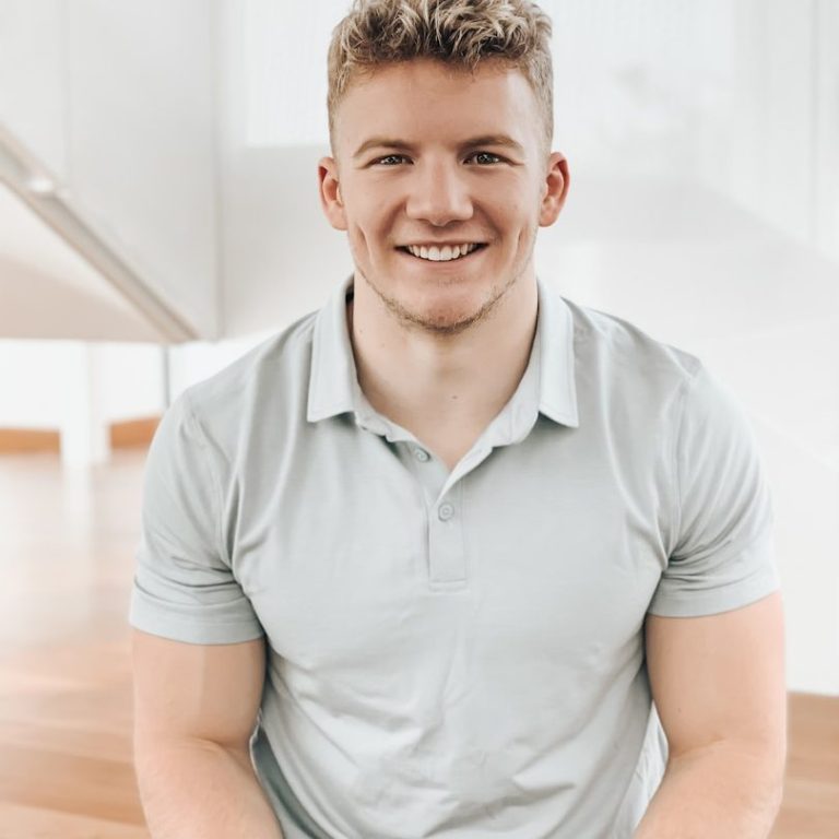 Executive function coaching for adults Smiling young man in a light-coloured polo shirt seated indoors.